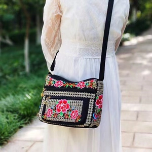 Detailed close-up of vibrant floral embroidery and multiple zippers on the ethnic crossbody bag