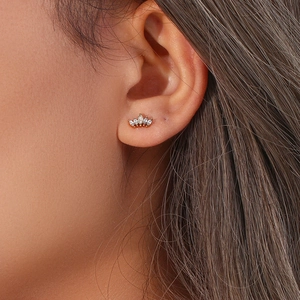 Close-up of golden crown stud earring with marquise-cut white zircons on ear model