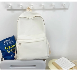 Detail view of large white canvas backpack with front zipper pocket on wall hook
