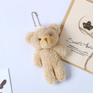 Detail of beige teddy bear plush pendant with soft curly fur and silver bead chain