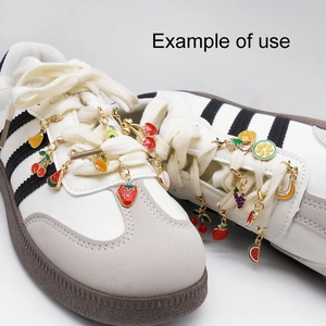 Enamel fruit charms on white sneakers including strawberry cherry and pineapple shapes