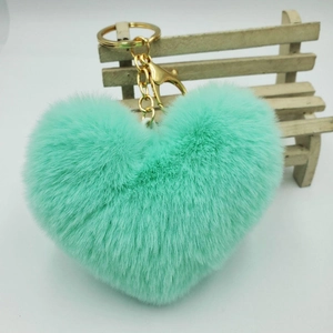 Close-up of fluffy mint green heart keychain in plush faux fur with gold lobster clasp