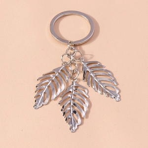 Detailed view of silver alloy keychain featuring three hollow leaf pendants on pink background