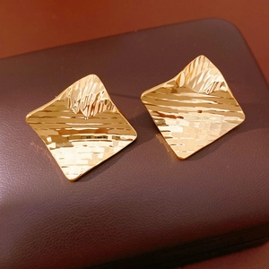 Détail de boucles d'oreilles plaquées or 18 carats avec surface martelée irrégulière