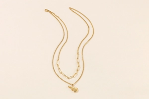Detail of golden double-layer chain necklace featuring a creative 3D guitar pendant