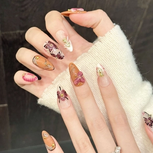 Chic almond press-on nails with orange-pink floral art, gold relief, and pearl accents