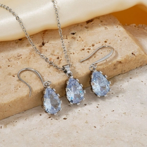 Detailed view of silver necklace and teardrop light blue gems on textured stone
