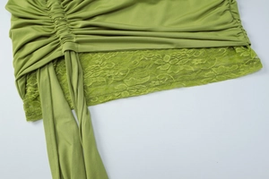 Detail of green lace trim and ruched fabric with decorative straps on a dress