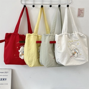 Detail of canvas drawstring bag showing cute cartoon embroidery and side fabric label