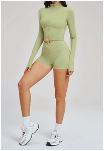 Detail view of sage green sports set with stand-up collar zip top and cross high-waist shorts
