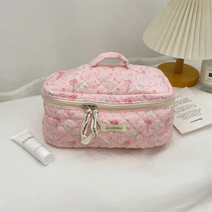 Pink quilted makeup bag with cute rabbit print and handle on soft white fabric