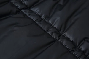 Macro view of black quilted synthetic fabric showing stitching detail and windproof texture