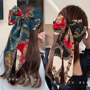 Detail view of large vintage chain print satin bow hair clips on long wavy hair