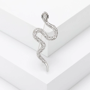 Sparkling silver snake brooch with inlaid crystal rhinestones on a white pedestal