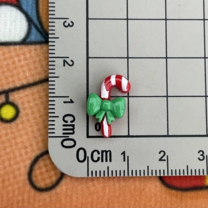 Macro shot of miniature candy cane resin accessory with ruler showing 1.5cm size detail