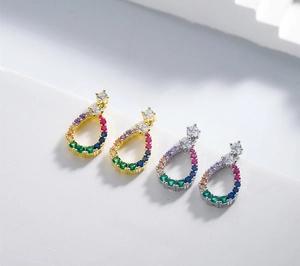 Close-up of teardrop earrings with colorful zircon stones in gold and silver plating