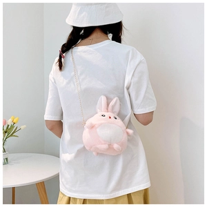Rear view of a pink plush bunny crossbody bag with a gold chain strap on a model