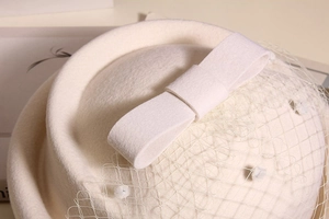 Detail of white wool felt beret featuring mesh veil and elegant bow embellishment