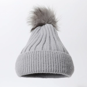 Close-up of grey knit beanie with large faux fur pom-pom and vertical ribbed texture