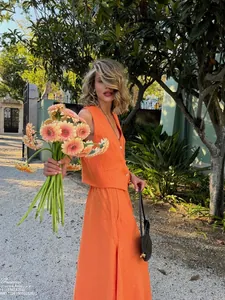 Detail of bright orange cotton linen vest and high-waisted trousers set for summer