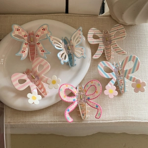 Close-up of matte resin hair claws with 3D daisies and cherry patterns on ceramic