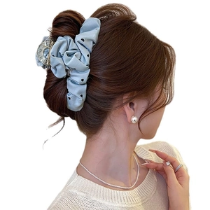 Light blue fabric hair claw clip with black heart polka dots shown on a model's hair