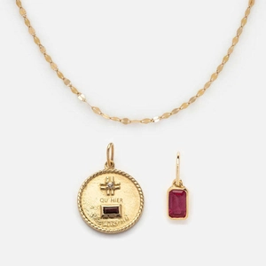 Close-up of golden necklace with birthstone pendants and Qu'hier Que Demain engraving