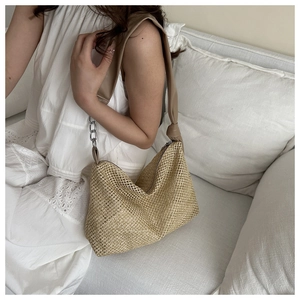 Detail of woven straw hobo bag featuring brown leather strap and silver metal chain accents