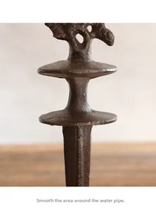 Close-up of vintage cast iron bird hose holder showing polished smooth metal surface