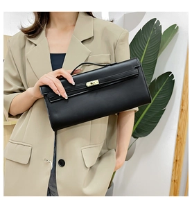 Detail of a black leather handbag featuring a gold metal twist lock and a top handle