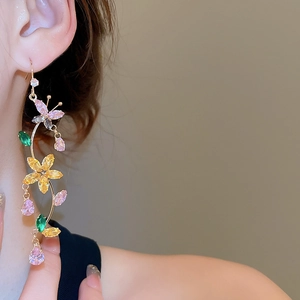 Macro shot of gold butterfly flower earrings with colorful zircon tassels on model