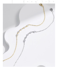 Dettaglio di bracciali in argento e oro con zirconi, chiusura a moschettone e catenella