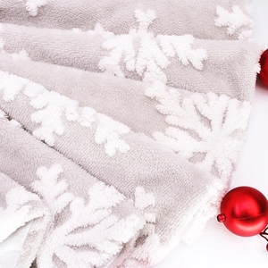 Close-up of white plush Christmas tree skirt with raised 3D snowflake texture and soft fur