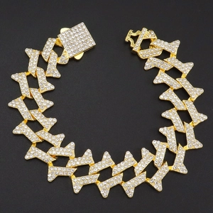 Iced-out gold Cuban chain bracelet with thorn-style links and crystal stones on black background