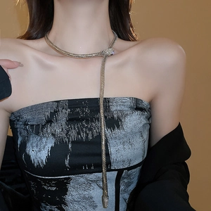 Detail showing crystal-encrusted snake-shaped necklace with shimmering tassel on a neck