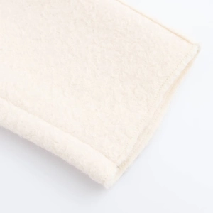 Detailed close-up showing ivory sherpa fleece texture and refined hem stitching on the coat