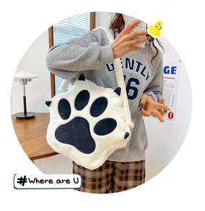 Close-up of fluffy white cat paw plush crossbody bag worn by a model in a casual indoor setting