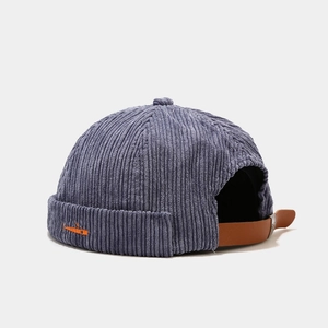 Detail of blue corduroy miki hat showing texture, orange embroidery and leather back strap