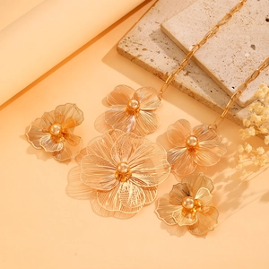 Detailed view of hollow floral jewelry set with golden finish on a stone pedestal