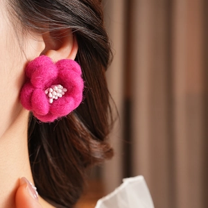 Gros plan de boucles d'oreilles fleurs en feutre rouge rose portées par un mannequin