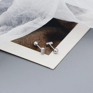 Macro detail of 925 silver stud earrings with sparkling cubic zirconia under silk paper