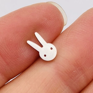 Miniature white rabbit ear stud in stainless steel held by hand to show 5mm small size