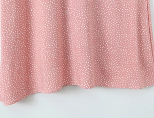 Close-up of pink polka dot dress hem showing high-quality fabric texture and drape