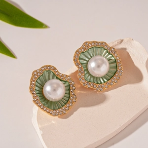 Gros plan sur les boucles d'oreilles coquillage avec perle et émail vert