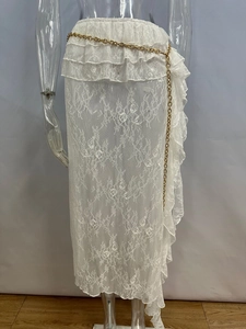Dettaglio gonna in pizzo bianco con vita a balze e cintura a catena in metallo dorato