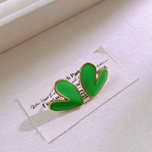 Close-up of green heart-shaped enamel earrings with elegant gold metallic borders