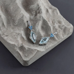 Marquise cut light blue gemstone earrings with navy accents on a textured stone surface