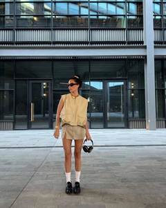 Draußen-Aufnahme einer beige ärmellosen Cargo-Weste mit plissiertem Saum und Reißverschluss