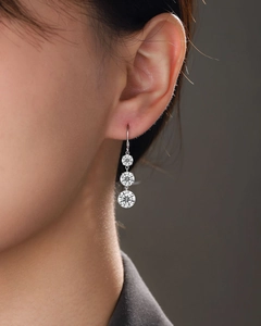 Detail of 925 silver drop earrings with three sparkling round moissanite stones on a model