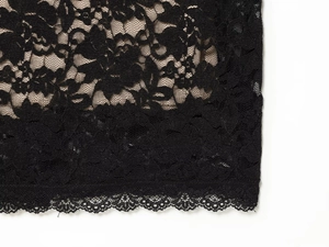 Close-up of black floral lace fabric with intricate patterns and scalloped edges for dresses